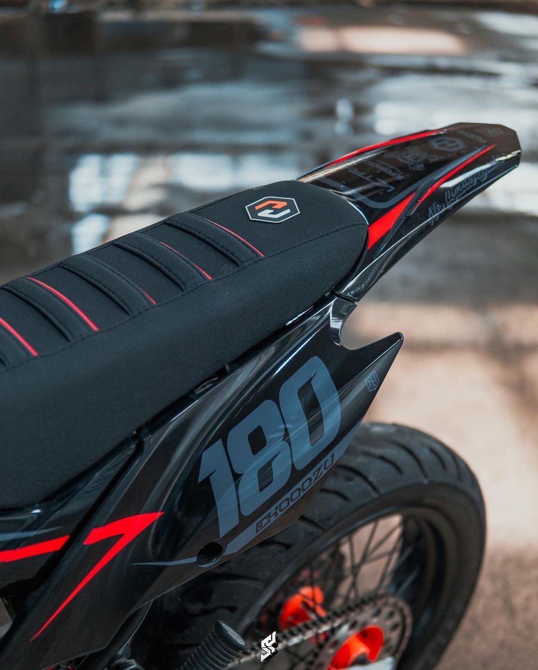 Banco preto com costuras vermelhas e rabeta de uma moto off-road