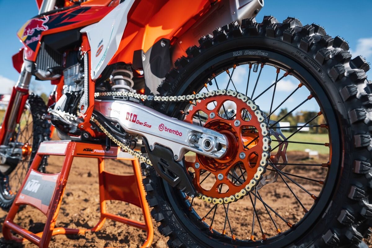 Roda traseira com pneu de cravos, coroa, corrente e balança de uma moto de motocross